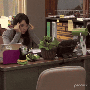 April from Parks and Recreation rubbing her temples at her desk